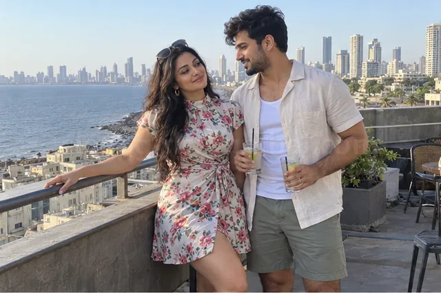 A woman in a short floral dress and a man in a linen shirt holding lime sodas on a sea-facing hotel rooftop in Mumbai